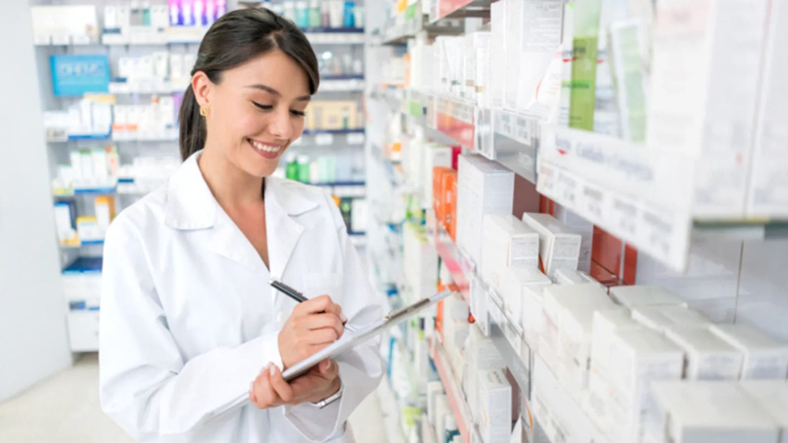 Mujer en farmacia tomando nota de los productos que hay en estantería.