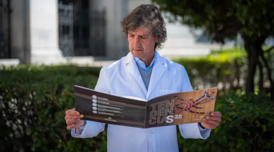 Hombre sosteniendo una revista en la que aparece el texto "tendencias 26"